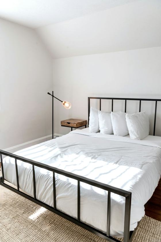 A bed with white sheets and pillows in a room