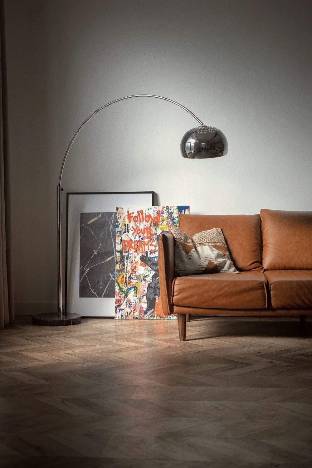 Brown wooden framed white padded armchair beside white wall