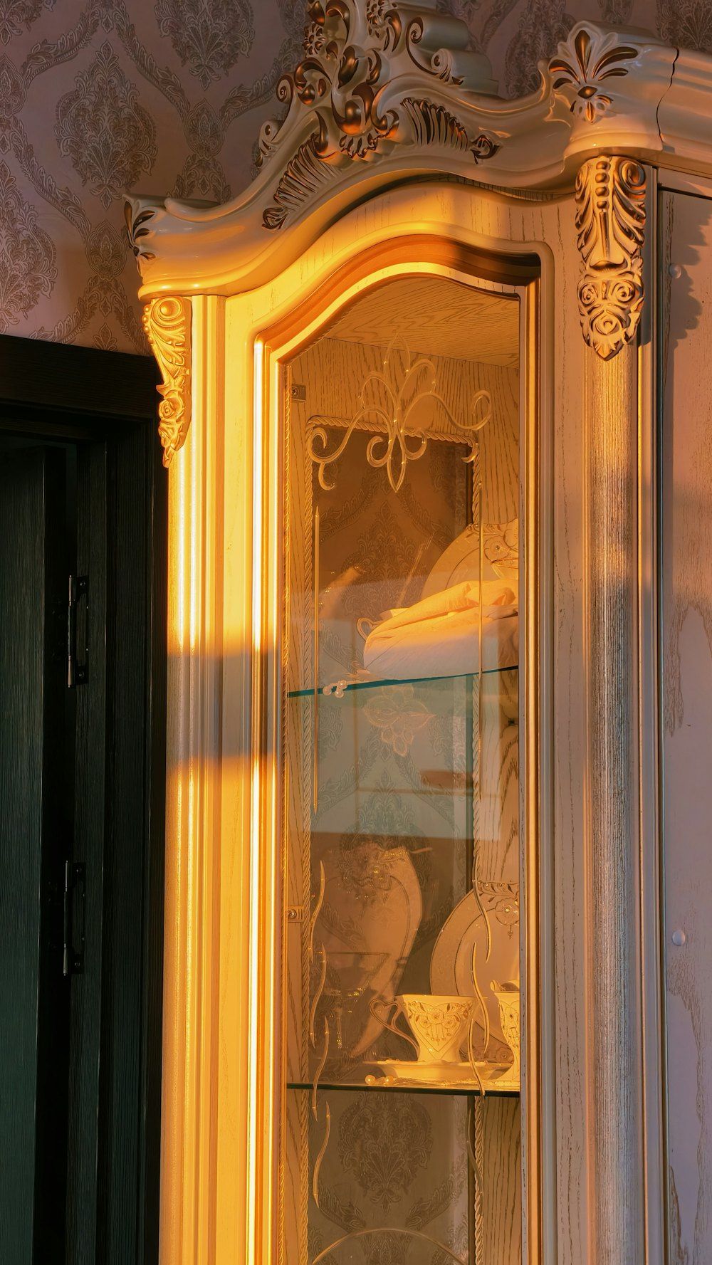 Ornate cabinet with glass doors illuminated by sunset light