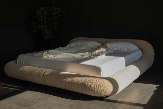 Modern bed with rounded headboard and white linens