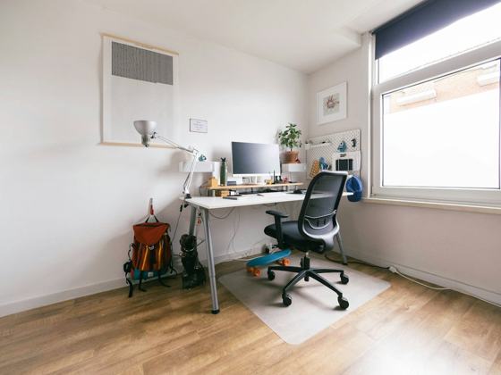 Black office rolling chair beside white wooden desk