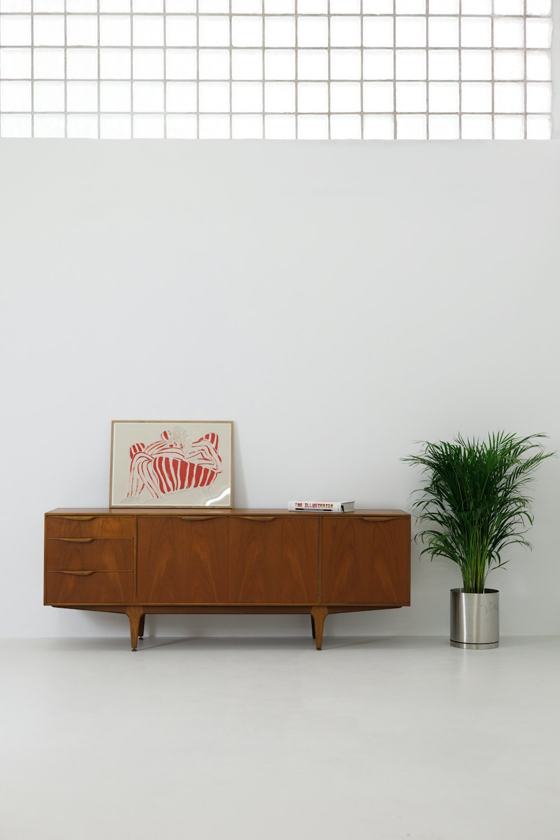 A white room with a wooden cabinet and a potted plant