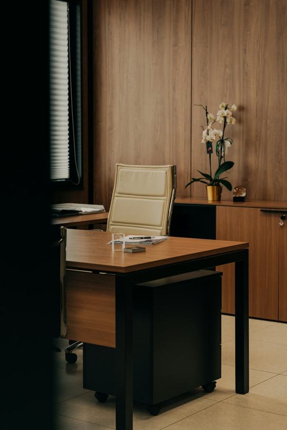 A desk with a chair and a vase of flowers