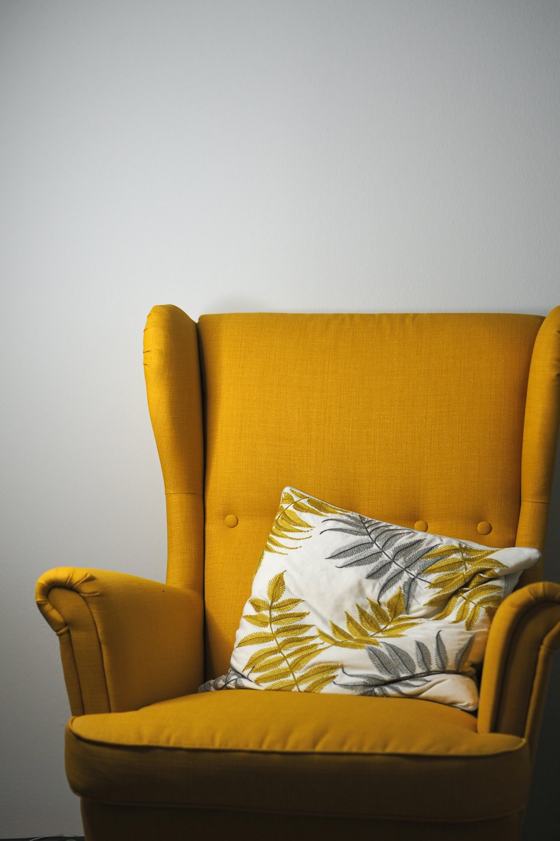 A yellow chair with a pillow on top of it