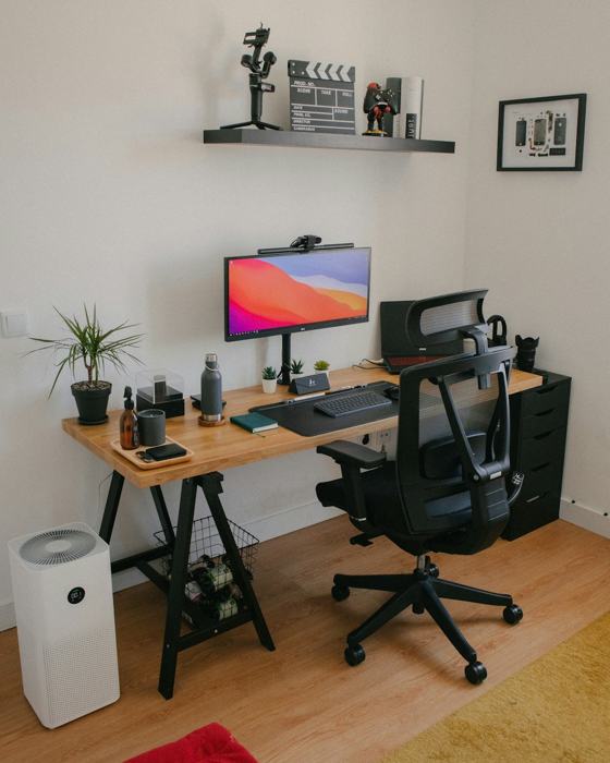 A desk with a computer and a chair in a room with a shelf