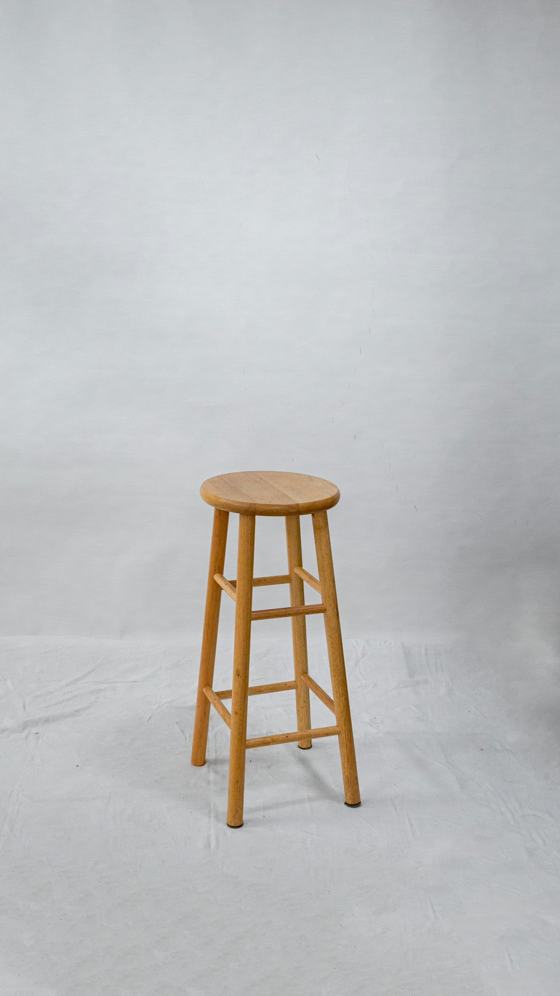 A wooden stool sitting on top of a white floor