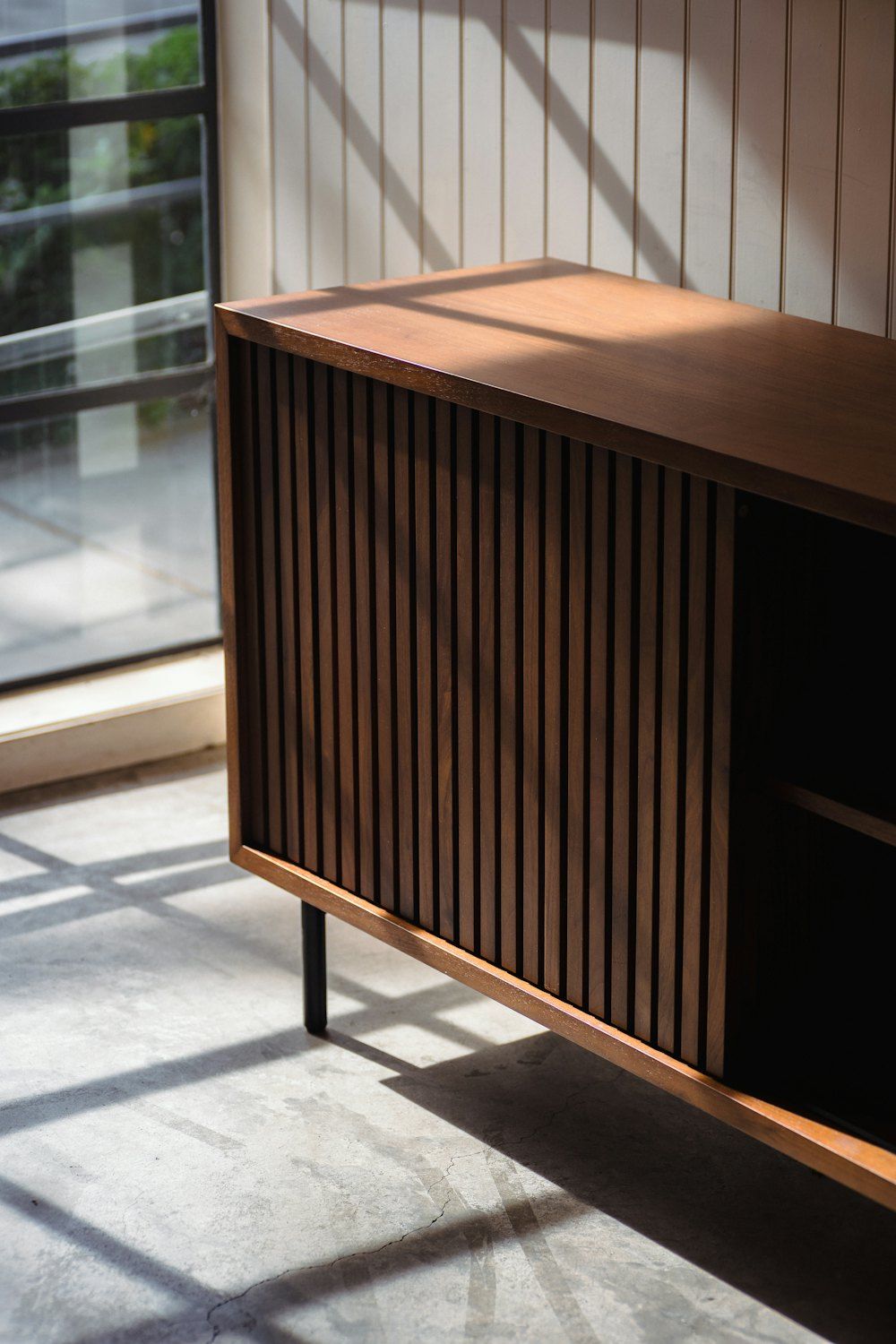 A wooden cabinet sitting in a room next to a window