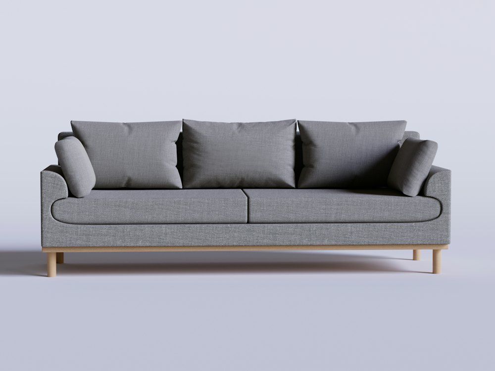 A gray couch with four pillows on it