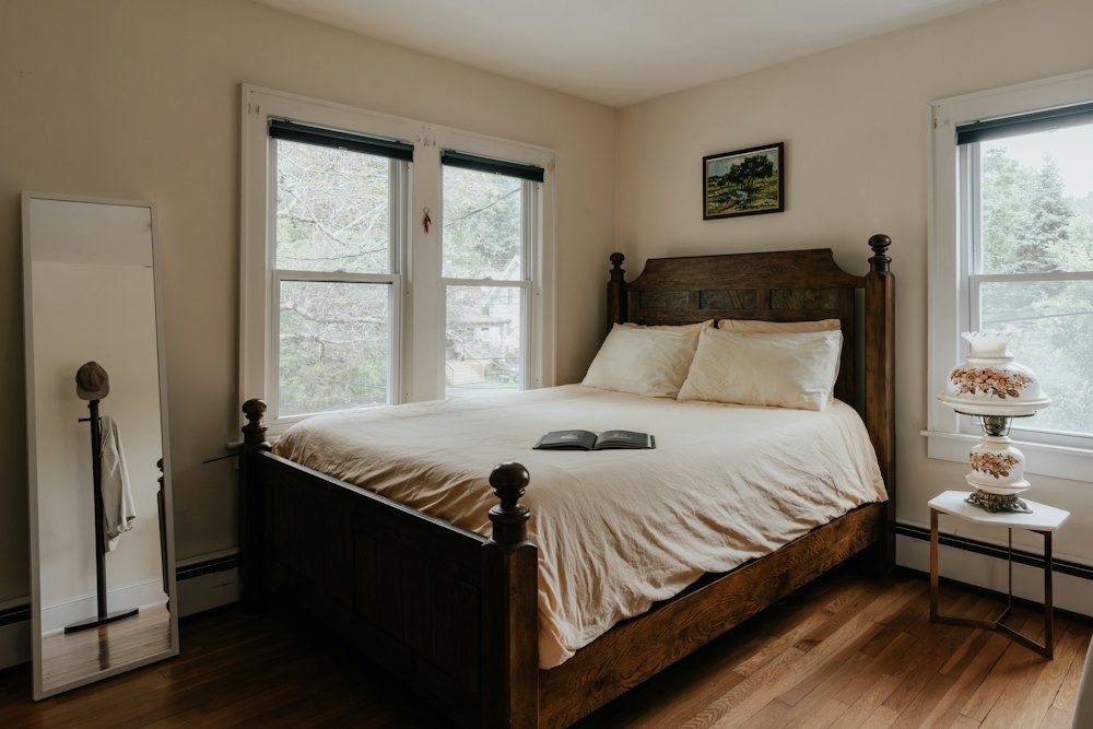 A bed sitting in a bedroom next to two windows