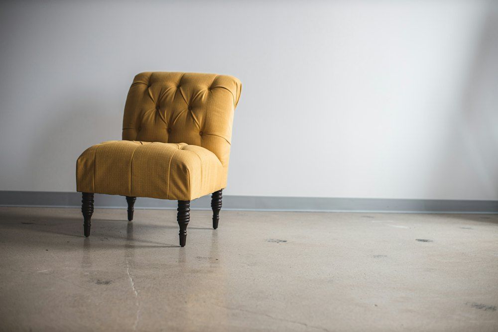 Person in black pants standing beside white leather armchair