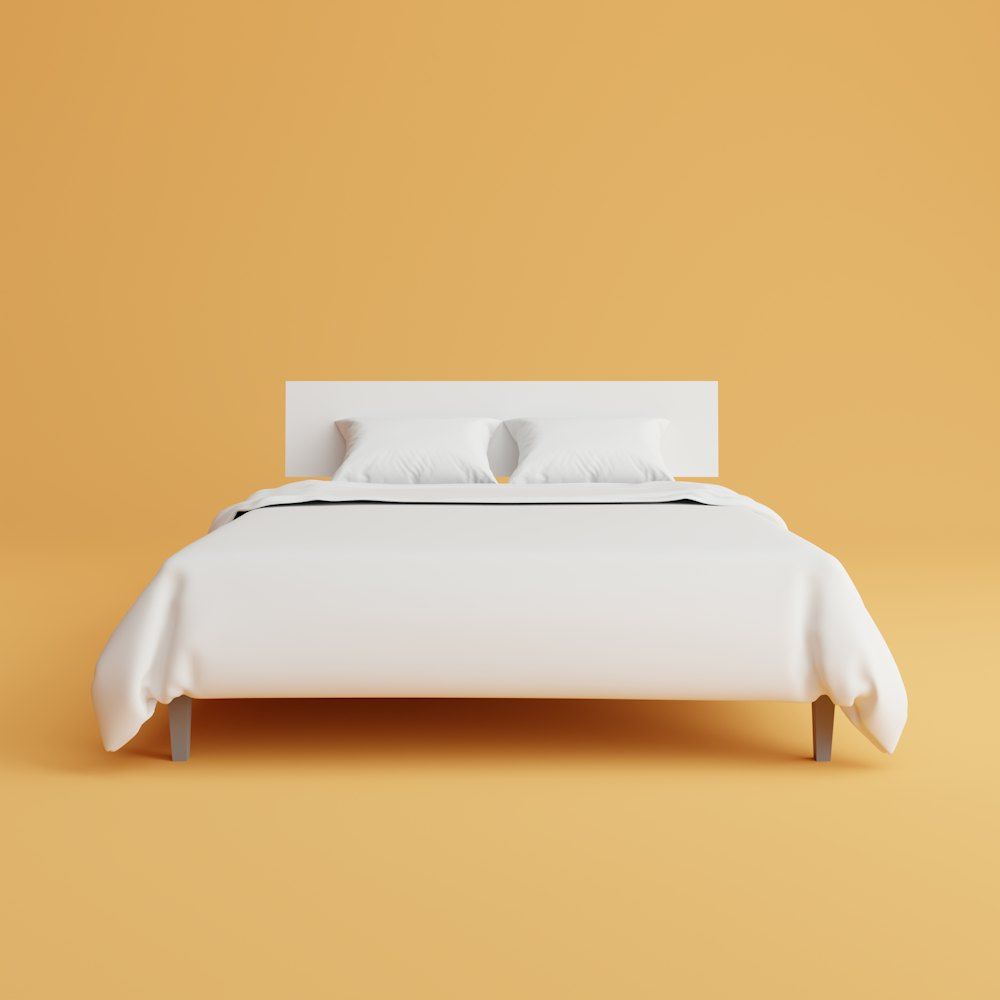 A bed with a white cover and pillows on top of it