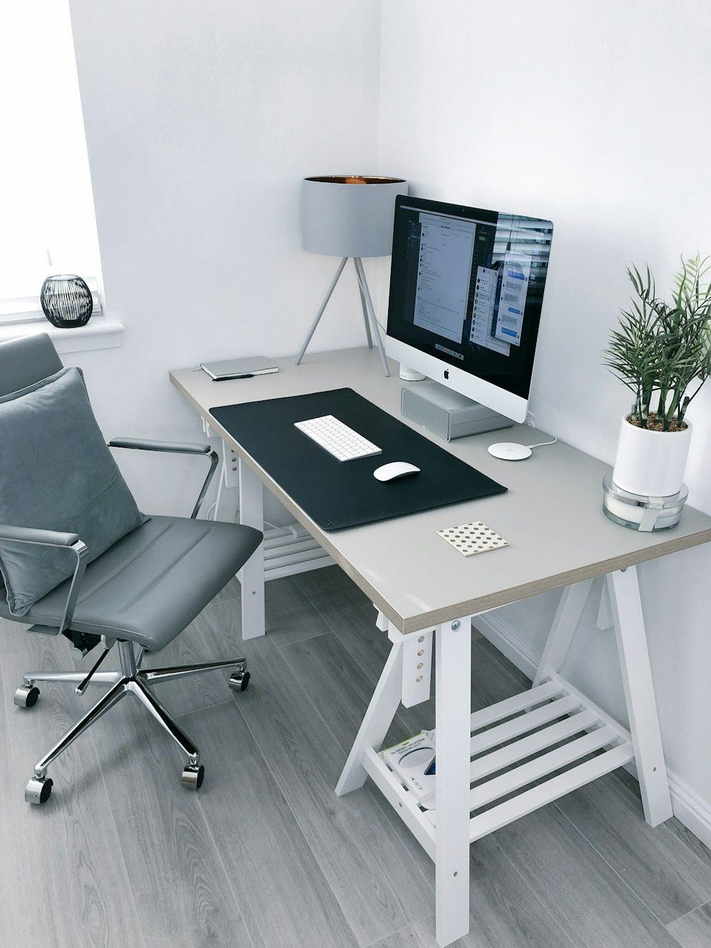 Gray leather office rolling armchair beside white wooden computer desk
