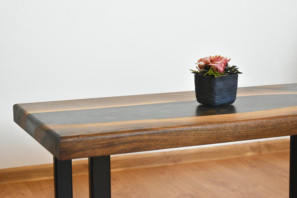 Red flower on blue ceramic vase on brown wooden table