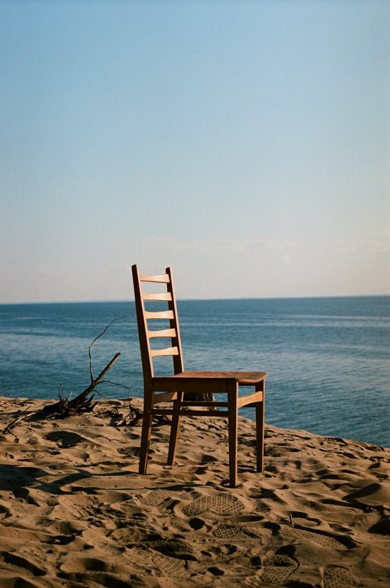 A wooden chair sitting on top of a sandy beach