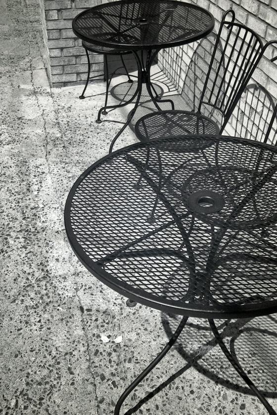 Two empty metal tables and chairs outside
