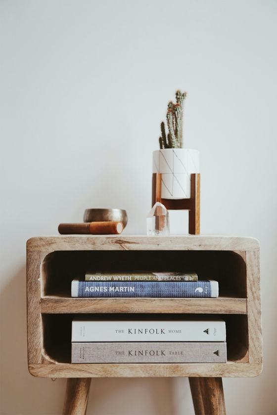 Books in brown wooden side table beside white wall