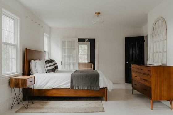 A bed room with a neatly made bed and a dresser