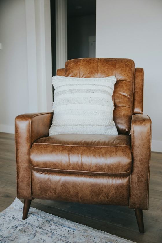 Brown leather armchair with white throw pillow