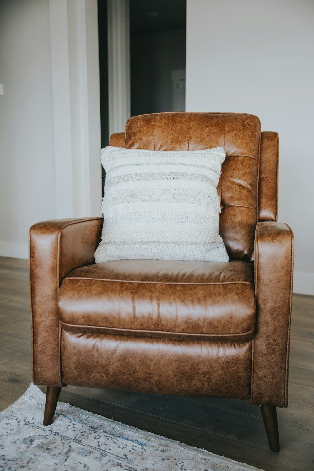 Brown leather armchair with white throw pillow