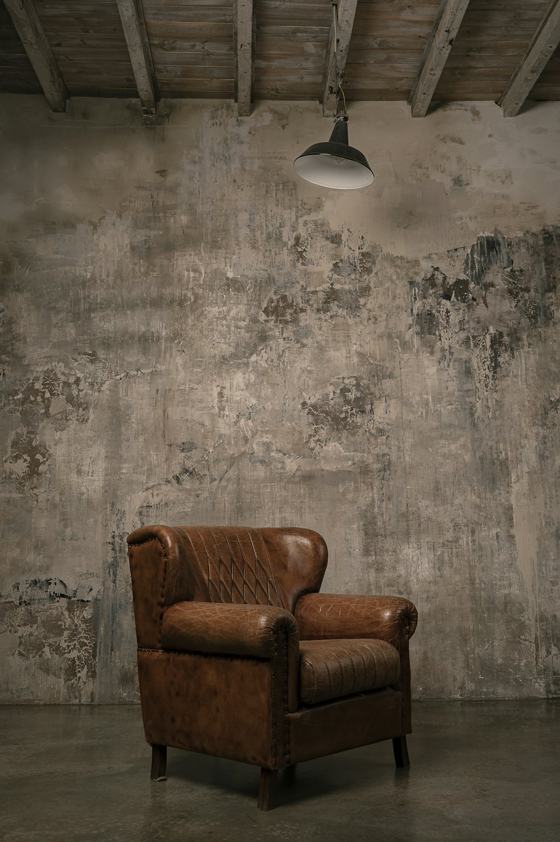 Brown wooden armchair beside white wall