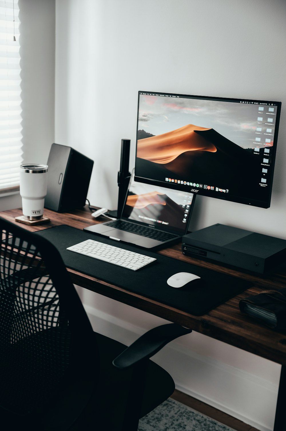 A home office workspace with a laptop, monitor, and keyboard on a wooden desk