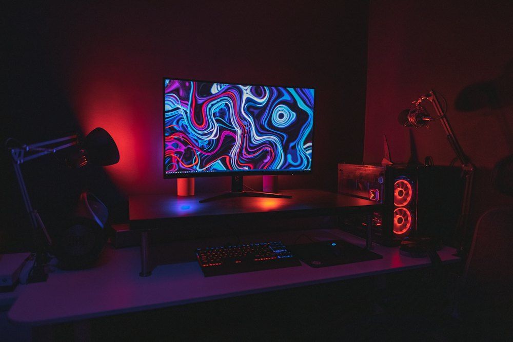 Black flat screen computer monitor turned on near black computer keyboard